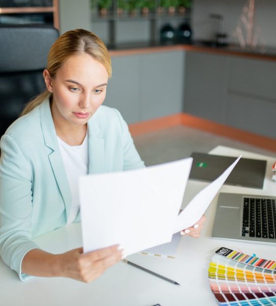 Elegant accountant or broker looking through financial papers while working in office